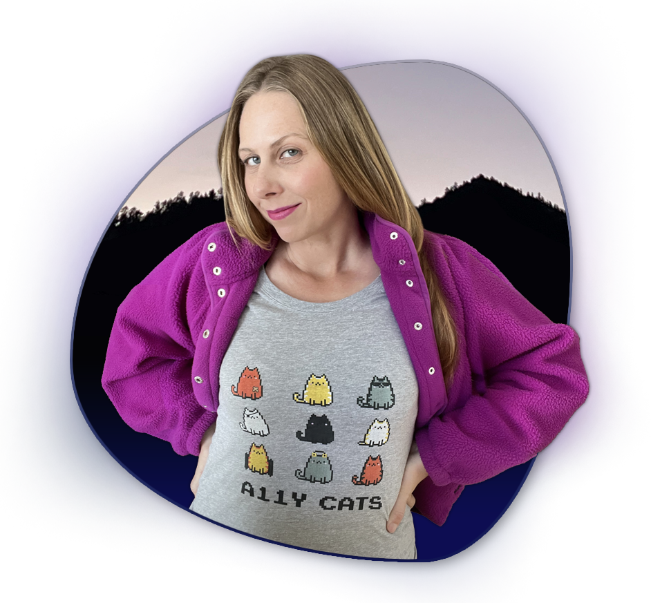 Carrie stands proudly in an A11y Cat shirt depicting cats with disabilities. She is in front of a blob shape with mountain gradient.