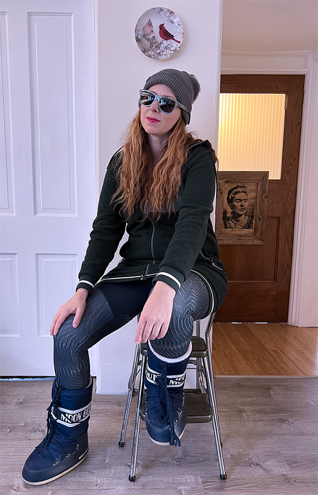 Carrie sitting on a stool, dressed in a gray winter beanie, and athletic clothes